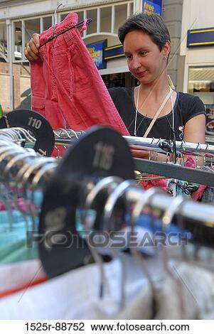 Stock Image - Mid adult woman choosing clothes in a clothing store. Fotosearch