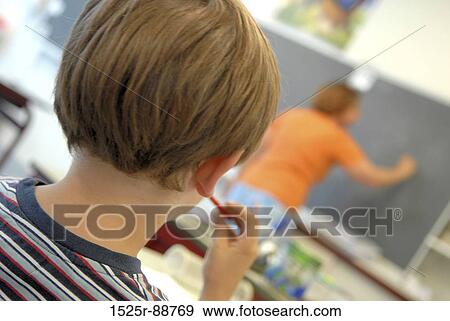 Rear view of a schoolboy with a teacher standing in the background View Large Photo Image Stock Photo - Rear view of a schoolboy with a teacher standing in the background. Fotosearch
