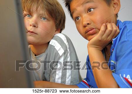 Stock Image - Two boys looking at a computer. Fotosearch