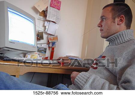 Young man using a computer View Large Photo Image Stock Photograph - Young man using a computer. Fotosearch