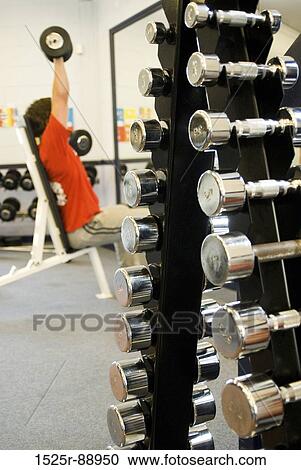 Man exercising with dumbbells in a gym View Large Photo Image Stock Image - Man exercising with dumbbells in a gym. Fotosearch