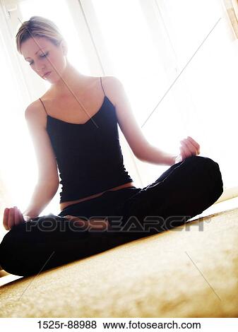 Stock Photo - Young woman meditating in the lotus position. Fotosearch