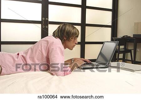 Man on bed with laptop View Large Photo Image Picture - Man on bed with laptop. Fotosearch