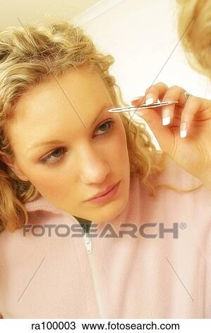 Stock Image - Woman plucking eyebrows. Fotosearch