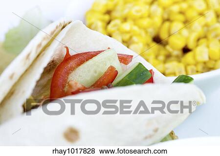 Stock Photo - A macro of a prepared taco with ingredients in th background. Fotosearch