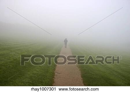 Stock Image - A man walking in to the mist. Fotosearch