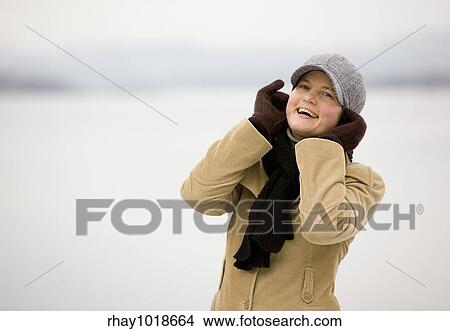 A young woman smiling by the ocean in winter. View Large Photo Image Picture - A young woman smiling by the ocean in winter.. Fotosearch