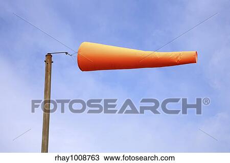 Stock Image - "An orange windsock, blowing in a strong wind. ". Fotosearch