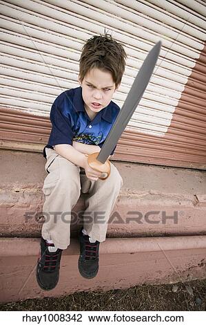 Stock Image - Angry Young Boy Pointing a Plastic Sword. Fotosearch