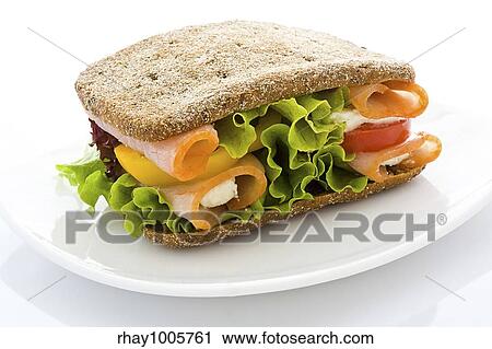 Stock Image - Appetizing sandwich from rye bread with a ham and salad on a white plate close upAppetizing sandwich from rye bread with a ham and salad on a white plate close up. Fotosearch
