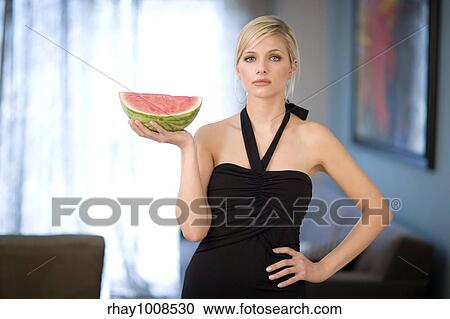Stock Image - Beautiful young woman holds a slice of watermelon. Fotosearch