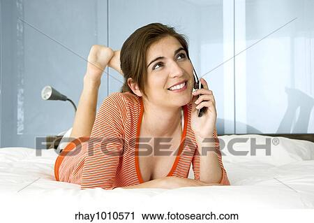 Stock Image - Beutiful happy woman in pajama talking at mobile phone. Fotosearch