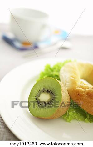Stock Photo - "Breakfast on the table ( coffee, kiwi, bagel, salad ) ". Fotosearch