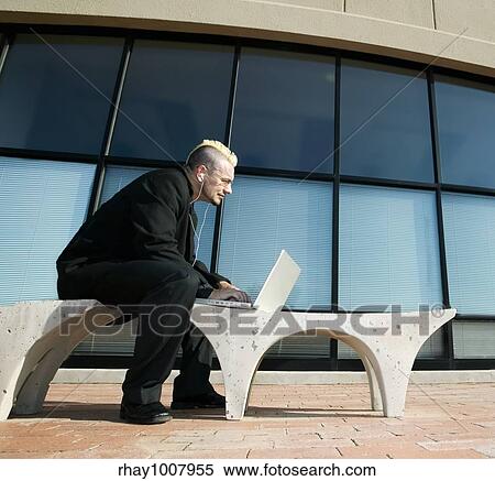 Businessman with a punk haircut works on a laptop computer in an office complex. View Large Photo Image Stock Photography - Businessman with a punk haircut works on a laptop computer in an office complex.. Fotosearch