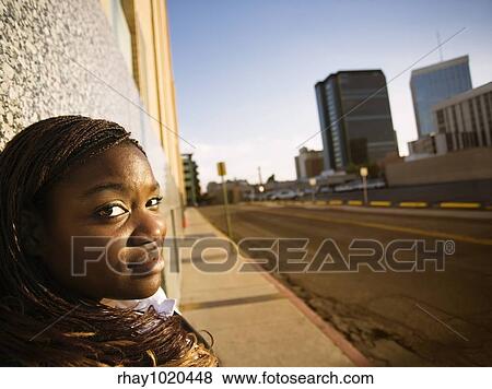 Stock Photo - Closeup of a pretty African American woman leaning on a building. Fotosearch