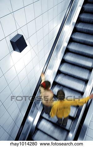 Stock Image - "Couple moving on escalator, with motion blur". Fotosearch