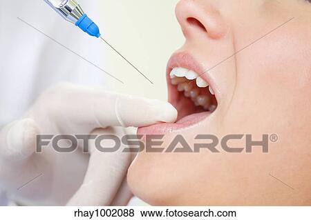 dentist holding a syringe and anesthetizing his patient View Large Photo Image Stock Photo - dentist holding a syringe and anesthetizing his patient. Fotosearch