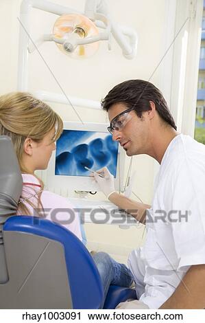 dentist talking to his patient and showing her a x-ray image of her teeth View Large Photo Image Stock Image - dentist talking to his patient and showing her a x-ray image of her teeth. Fotosearch