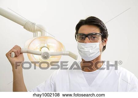 Stock Photo - dentist turning on examination light. Fotosearch