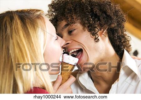 Picture - domestic life: interracial couple sharing an ice cream. Fotosearch