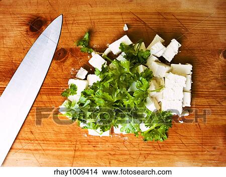 Picture - feta pieces with parsley on cutting board. Fotosearch