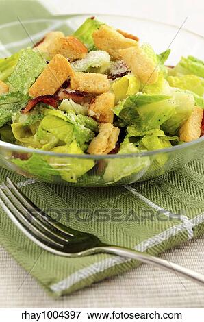 Fresh caesar salad with croutons and bacon bits served in a glass bowl View Large Photo Image Stock Photo - Fresh caesar salad with croutons and bacon bits served in a glass bowl. Fotosearch