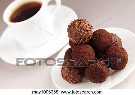 Stock Photo - Gourmet chocolate truffles on a plate with a cup of coffee. Fotosearch