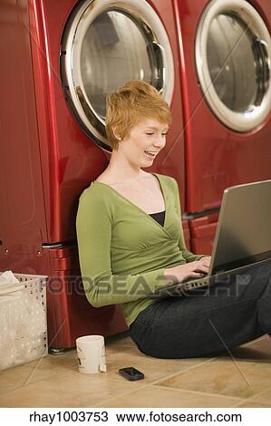 Happy woman with laptop waiting for laundry View Large Photo Image Stock Image - Happy woman with laptop waiting for laundry. Fotosearch