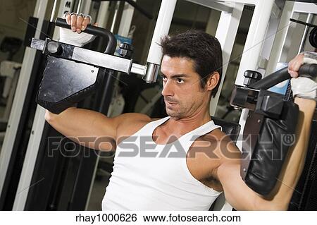 health club: guy in a gym doing weight lifting View Large Photo Image Stock Photograph - health club: guy in a gym doing weight lifting. Fotosearch