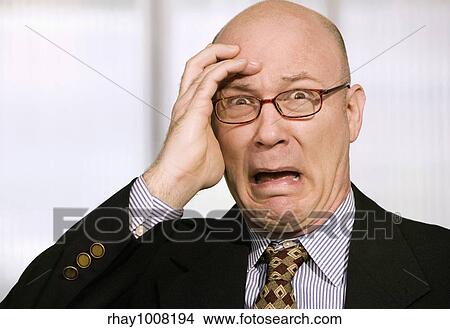 Picture - Horrified businessman with a hand to his forehead. Fotosearch