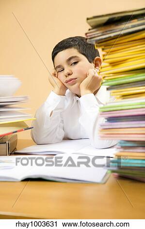 Stock Image - little boy getting bored of his homeworks. Fotosearch