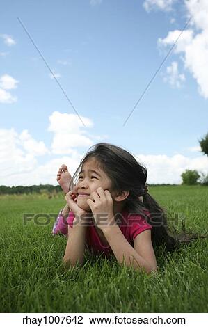 Little girl lying on grass in summer View Large Photo Image Stock Image - Little girl lying on grass in summer. Fotosearch