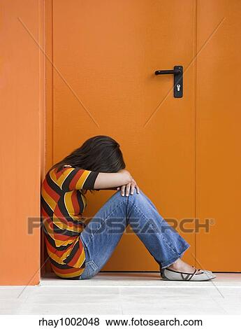 Loneliness woman on a orange door with hands over the knees View Large Photo Image Stock Photo - Loneliness woman on a orange door with hands over the knees. Fotosearch