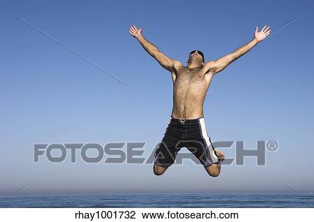 Stock Image - Man jumping on the beach. Fotosearch