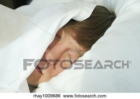 "Man sleeping under white covers, ready to wake in the morning light" View Large Photo Image Stock Photograph - "Man sleeping under white covers, ready to wake in the morning light". Fotosearch