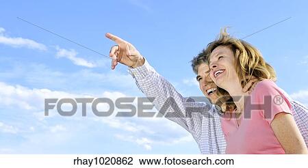 Stock Image - Mature romantic couple of baby boomers looking at the sky. Fotosearch