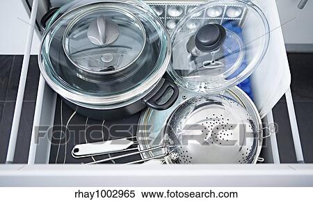 "Metal pans with glass covers, a colander and a sieve in an open kitchen boxMetal pans with glass covers, a colander and a sieve in an open kitchen box" View Large Photo Image Stock Photography - "Metal pans with glass covers, a colander and a sieve in an open kitchen boxMetal pans with glass covers, a colander and a sieve in an open kitchen box". Fotosearch