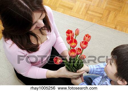 Stock Photograph - Mother receiving a bouquet of flowers from her son on mother's day. Fotosearch