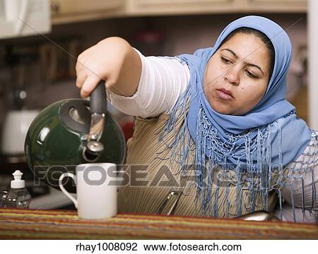 Muslim woman wearing a head scarf in a western kitchen pouring tea View Large Photo Image Stock Image - Muslim woman wearing a head scarf in a western kitchen pouring tea. Fotosearch