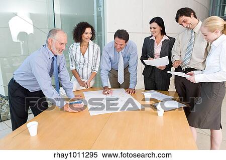 office workers standing around meeting table View Large Photo Image Stock Photography - office workers standing around meeting table. Fotosearch