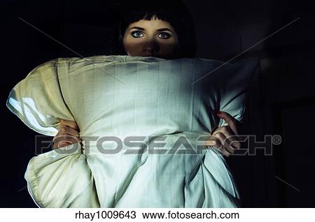Stock Image - old movie still styled image of a woman holding a pillow in the darkness. Fotosearch