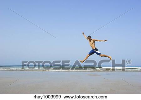 Picture of a young man jumping on the beach View Large Photo Image Stock Photo - Picture of a young man jumping on the beach. Fotosearch