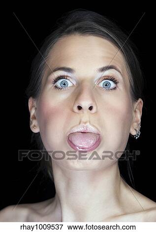 Stock Photo - portrait a of a beautiful woman sticking out her tongue isolated on black. Fotosearch
