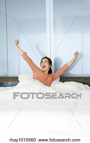 Stock Image - Portrait of a beautiful woman on a bed waking up. Fotosearch