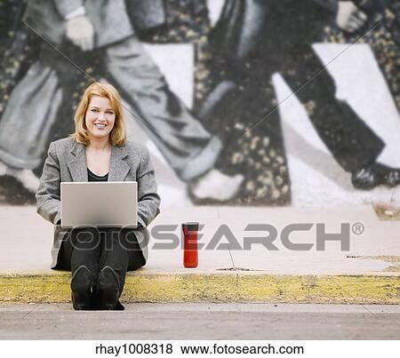 Pretty smiling woman with a laptop computer sitting on the sidewalk View Large Photo Image Stock Photo - Pretty smiling woman with a laptop computer sitting on the sidewalk. Fotosearch