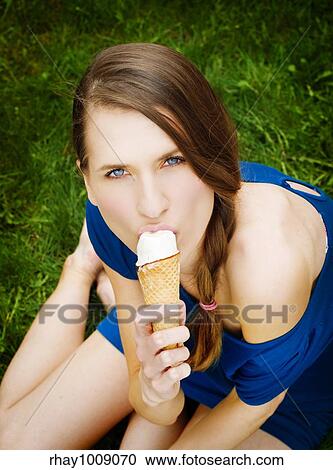 pretty young woman eating icecream while sitting on the ground View Large Photo Image Stock Image - pretty young woman eating icecream while sitting on the ground. Fotosearch