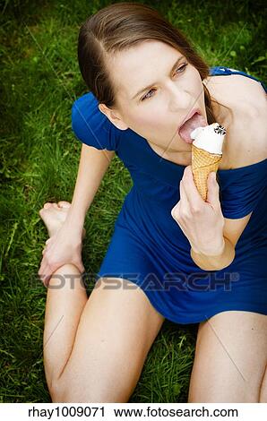 pretty young woman eating icecream while sitting on the ground View Large Photo Image Stock Image - pretty young woman eating icecream while sitting on the ground. Fotosearch