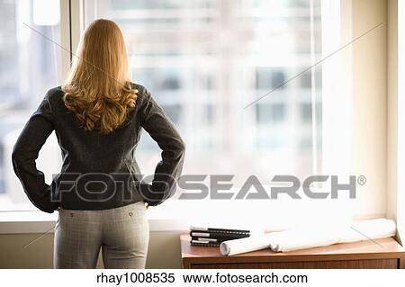 Rear view of woman looking out office window View Large Photo Image Stock Photography - Rear view of woman looking out office window . Fotosearch