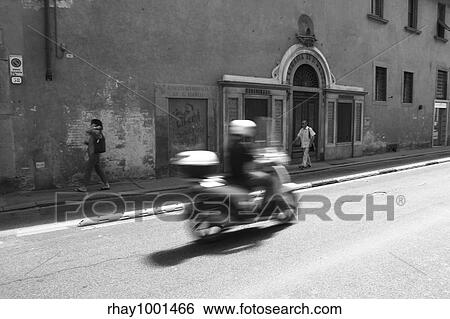 "Scooter speeding down the streets of Florence, Italy. Apart from cars the scooter is the most common means of transport in most Italian cities. Shot in monochrome. " View Large Photo Image Stock Photograph - "Scooter speeding down the streets of Florence, Italy. Apart from cars the scooter is the most common means of transport in most Italian cities. Shot in monochrome. ". Fotosearch