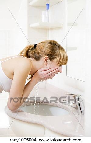 side profile of a young woman washing her face in a basin View Large Photo Image Picture - side profile of a young woman washing her face in a basin. Fotosearch